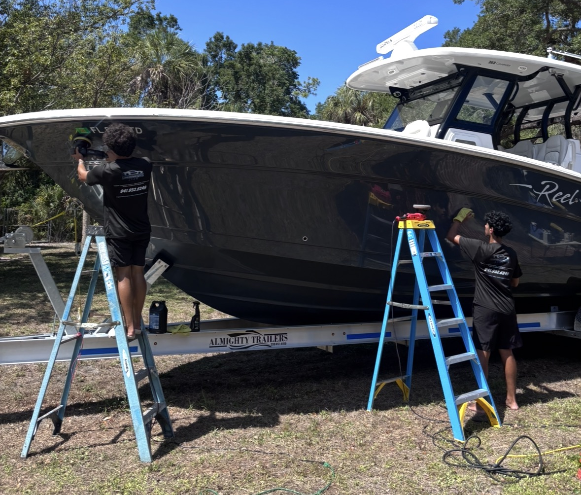 Dean and Jonah polishing the hull of a large boat on ladders